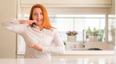 Mutfak eller eller büyük gösterilen ve büyük boy işareti, ölçü birimi sembolü ile Kızıl saçlı kadın. Kameraya bakarak gülümsüyordu. Ölçüm kavramı.