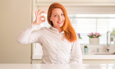 Mutfak el ve parmaklar ok işaretiyle yapıyor olumlu gülümseyen, Kızıl saçlı kadın. Başarılı ifade.
