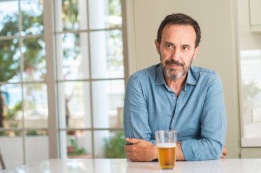 Orta yaş erkek ciddi düşünme akıllı yüzünde kendinden emin bir ifade ile bira içmek