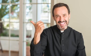 El ve parmak ile yukarı dönük mutlu yüz gülümseyen ile Hıristiyan rahip adam