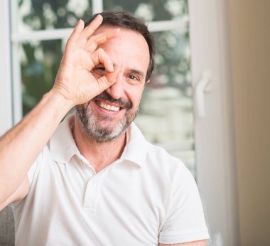 Mutlu yüz el parmaklarının arasından seyir göz üzerinde ok işaretiyle yapıyor gülümseyen yakışıklı orta yaş adamla