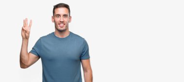 Gösterilen ve parmakları ile işaret yakışıklı genç casual adam kendinden emin ve mutlu gülümseyerek iken üçüncü.