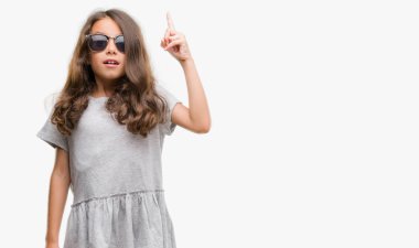 Esmer Latin kız başarılı fikirle parmak işaret güneş gözlüğü takıyor. Çıktıktan ve mutlu. Bir numara.