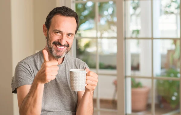 中年男子喝咖啡在一杯快乐的大微笑做 拇指与手指 优秀的标志 — 图库照片