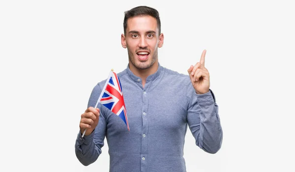 ハンサムな若い男のアイデアに驚いてイギリスの旗を保持または幸せそうな顔 ナンバーワンと人差し指の質問 — ストック写真