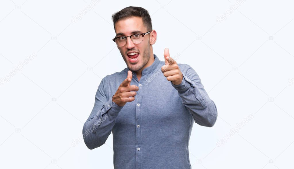 Handsome young elegant man wearing glasses pointing fingers to camera with happy and funny face. Good energy and vibes.