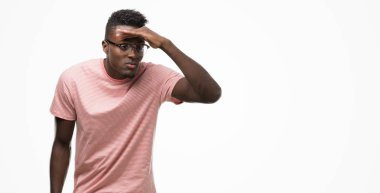 Çok mutlu ve gülümseyen uzakta el ile üzerine kafa seyir pembe t-shirt giyen genç Afro-Amerikan adam. Arama kavramı.