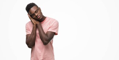 Rüya ve elleri ile kapalı gözler gülümseyen birlikte poz pembe tişört uyku giyen genç Afro-Amerikan adam yorgun.