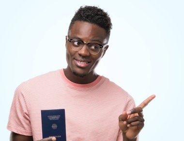Alman pasaportu çok mutlu el ve parmak ile tarafına işaret tutan genç Afro-Amerikan adam