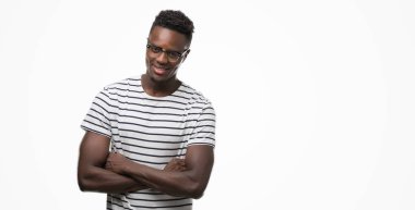 Gözlük ve lacivert t-shirt mutlu yüz ile gülümseyen genç Afro-Amerikan adam kameraya seyir silah geçti. Olumlu bir kişi.