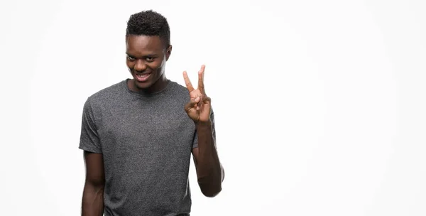 若いアフリカ系アメリカ人を示すと指で上向きのグレーの シャツを着て番号自信を持って 幸せな笑みを浮かべている間 — ストック写真
