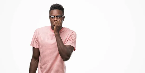 不安や 緊張を探してピンクの シャツを着て若いアフリカ系アメリカ人男の爪をかむ口に手します 不安の問題 — ストック写真