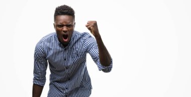 Öfkeli ve sinirli sinirli ve öfke ile bağırarak süre öfkeli yumruk yükselterek mavi gömlek giymiş genç Afro-Amerikan adam. Öfke ve agresif kavramı.