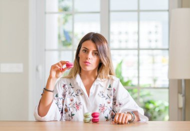 Genç kadın evde macarons kendine güvenen bir ifade ile acımak yüz ciddi düşünüyorum yeme.