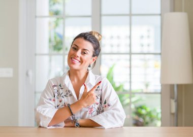 Genç kadın, neşeli bir gülümseme ile yüz el ile işaret Anasayfa ve kameraya bakarak yüzündeki mutlu ve doğal ifade ile yan kadar parmak.