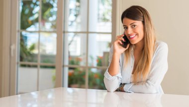 Genç kadın mutlu gülümseyerek smartphone kullanarak, cep telefonu evde seyir holding