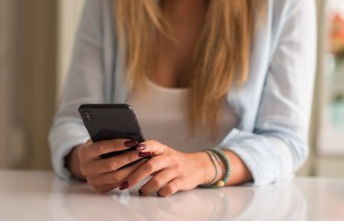 Evde akıllı telefon kullanan bir kadın.