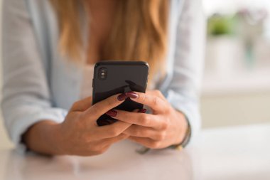 Evde akıllı telefon kullanan bir kadın.