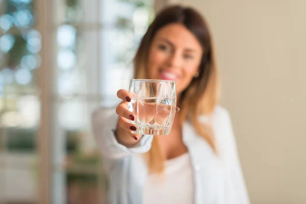 家庭での水のガラスを押しながら笑みを浮かべて美しい若い女性 ライフ スタイルのコンセプト — ストック写真