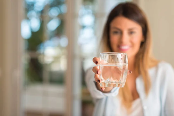 家庭での水のガラスを押しながら笑みを浮かべて美しい若い女性 ライフ スタイルのコンセプト — ストック写真