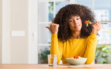 El ve parmak kadar mutlu yüz gülümseyen ile Afrikalı-Amerikalı kadın evde makarna salatası yemek işaret