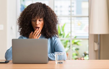 Sessizlik içinde gizli konsept dizüstü bilgisayar evde el ile kapak ağız şok utanç ile hata için korku, ifade kullanan Afrikalı-Amerikalı kadın korkuyor