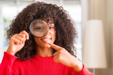 Meraklı Afrikalı-Amerikalı kadın el ve parmak ile işaret çok mutlu Büyüteç aracılığıyla arıyor