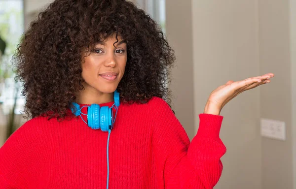 Afroamerikanerin Mit Kopfhörer Lächelt Fröhlich Und Zeigt Mit Der Handfläche — Stockfoto