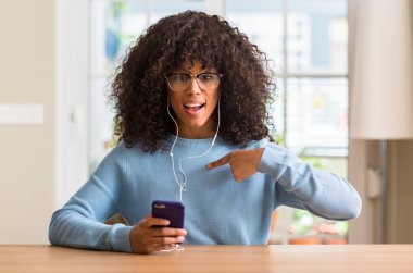 Kendisi için sürpriz yüz işaret parmağı ile Smartphone kullanarak güzel bir Afrikalı-Amerikalı kadın