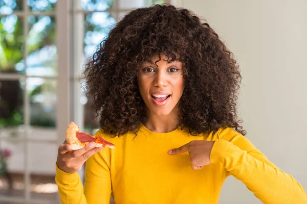 Afrikalı-Amerikalı kadın pepperoni pizza dilimi sürpriz yüz işaret parmağı kendine yemeye hazır