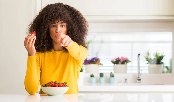 非洲裔美国妇女吃草莓在家里指着手指到相机和你 正面和自信的手势从前面 — 图库照片