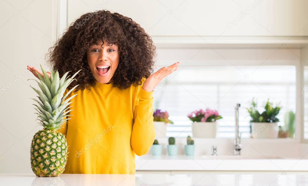 African american woman and pineapple tropical fruit very happy and excited, winner expression celebrating victory screaming with big smile and raised hands