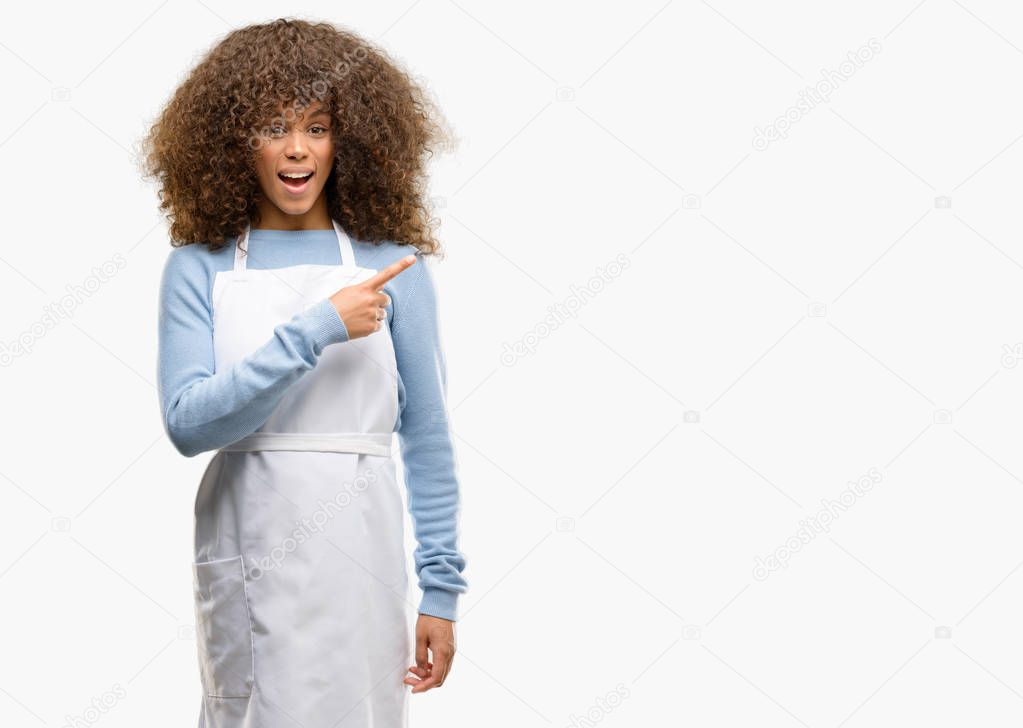 African american shop owner woman wearing an apron pointing away side with finger