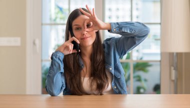 Mutlu yüz el parmaklarının arasından seyir göz üzerinde ok işaretiyle yapıyor gülümseyen ile akıllı telefon kullanan genç kadın