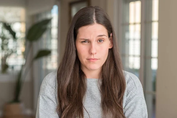 Ev şüpheci ve sinir, onaylamayan ifade yüz çapraz kolları olan genç güzel kadın. Negatif kişi.