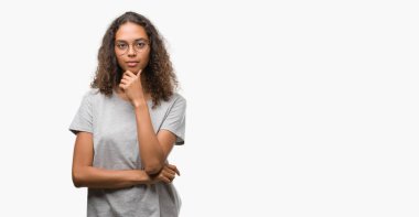 Emin çapraz kollar ve çeneme kaldırdı el ile gülümseme ile kameraya bakarak gözlüklü güzel genç İspanyol kadın. Pozitif düşünce.