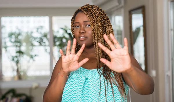 Afrikalı-Amerikalı kadın şokta bağırarak evde korkuyor ve korku ifade dur hareketi el ile ile çok korkmuş. Panik kavramı.