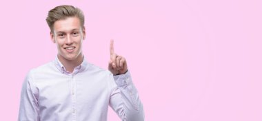 Genç yakışıklı sarışın adam bir fikir ya da soru işaret parmağı ile gülen yüz, sürpriz bir numara