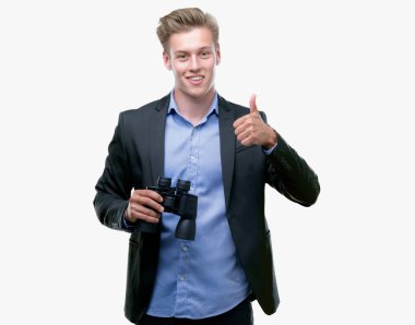 Genç yakışıklı sarışın adam ok işareti, başparmak ile parmak, mükemmel işareti yapıyor kocaman bir gülümseme ile dürbün ile mutlu seyir