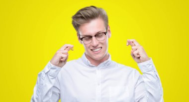 Umut ve gözleri kapalı geçiş parmaklarıyla gülümseyen genç yakışıklı sarışın adam. Şans ve batıl kavramı.