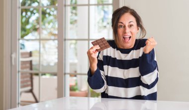 Duygu tezahürat yeme çikolata bar gurur çığlık ve zafer ve başarı çok heyecanlı, kutluyor kadın orta yaşlı