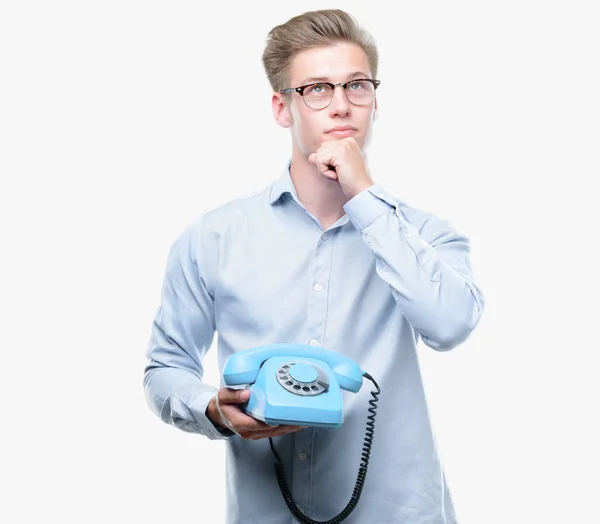 Jovem Bonito Loiro Homem Segurando Telefone Vintage Rosto Sério Pensando — Fotografia de Stock