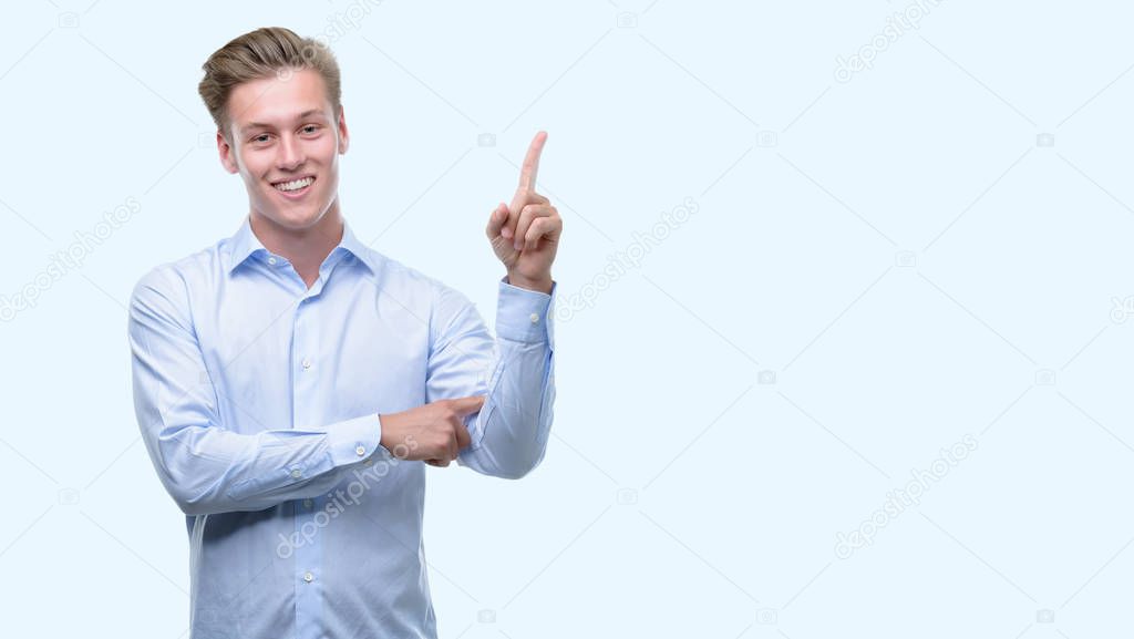 Young handsome blond man very happy pointing with hand and finger to the side