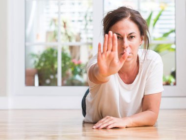 Orta yaşlı kadın açık eliyle dur işareti ile ciddi ve kendine güvenen ifade, savunma hareketi yapıyor