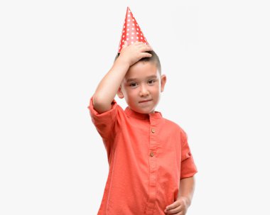 Koyu saçlı küçük çocuk Doğum günü şapkası kafasına, el ile vurguladı şok utanç ve sürpriz suratla, öfkeli ve sinirli. Korku ve hata için üzgün.