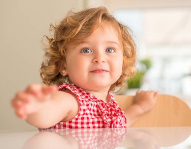 Evde dikkat isteyen tutmak için soran gülümseyen güzel sarışın çocuk.