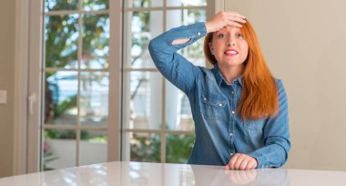 Kızıl saçlı kadın evde kafasına, utanç ve sürpriz yüz, öfkeli ve sinirli ile şok el ile vurguladı. Korku ve hata için üzgün.