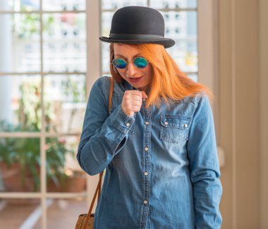 Melon şapka ve güneş gözlüğü hasta ve soğuk veya bronşit için semptom olarak öksürük duygu giymiş şık Kızıl saçlı kadın. Sağlık kavramı.