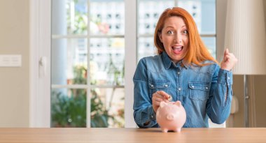 Kızıl saçlı kadın evde domuzcuk gurur çığlık ve zafer ve başarı çok kutluyor, duygu tezahürat heyecanlı bankada para kazandırır