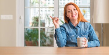 Bir fincan kahve çok mutlu el ve parmak ile tarafına işaret tutan Kızıl saçlı kadın